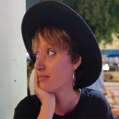 Elizabeth Brico headshot looking sideways in a black hat